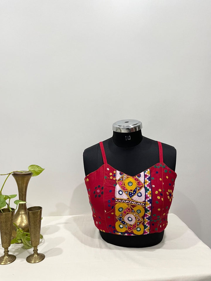 Red blouse with mirror work embroidery and spaghetti strap in kutchi style for Navratri wear 